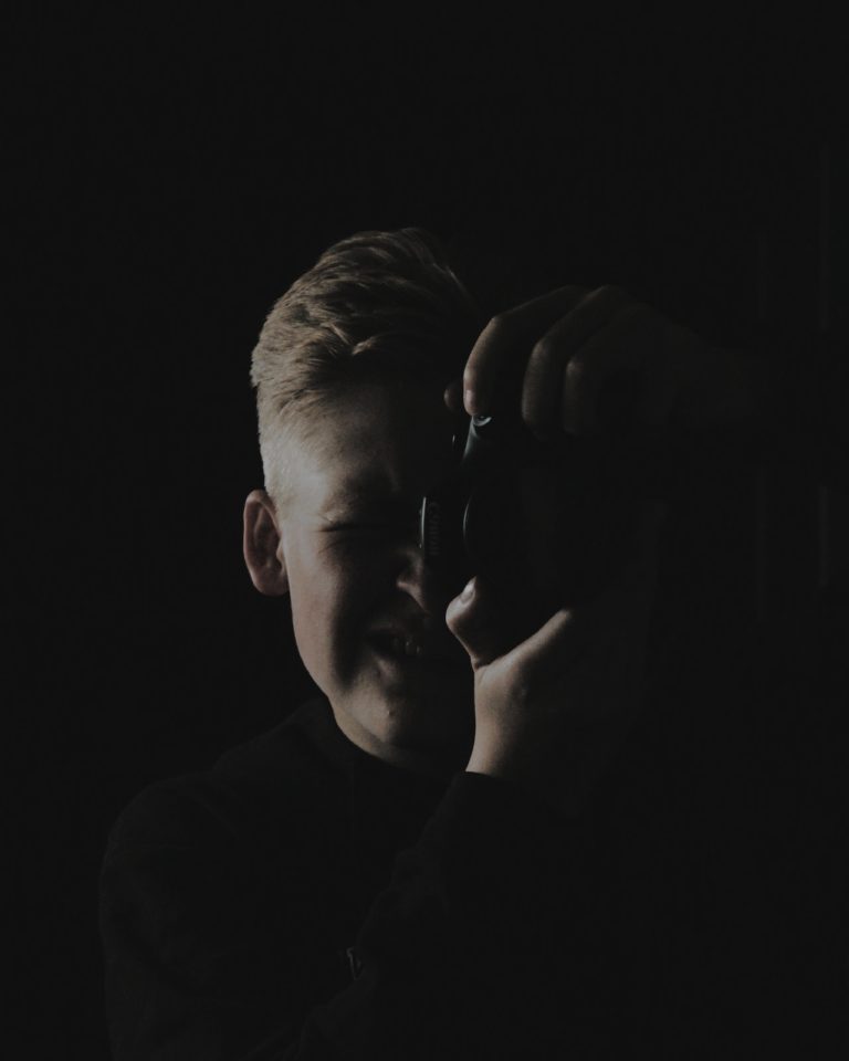 Zelfportret van Anne. Donkere foto genomen in een spiegel, het licht schijnt op Anne's gezicht vanaf de linkerkant. De camera bedekt de rechterkant van zijn gezicht.